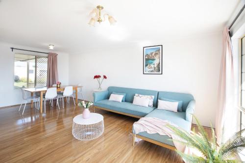 a living room with a blue couch and a table at Hallett Cove House 6Bed 3Bath Full Kitchen Fast Wifi 5TV Netflix Espresso-Perfect for large families in Halletts Cove