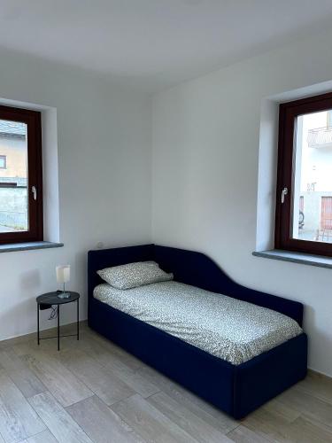 a blue bed in a room with two windows at À la Bouteucca in Fenis