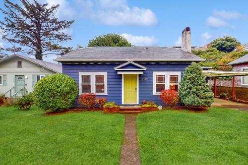 a blue house with a yellow door in a yard at Cliff Retreat in Rockaway Beach