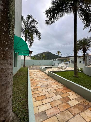 a brick walkway with a green umbrella next to a building at Desfrute bons momentos a beira mar com diária 24h in Caraguatatuba
