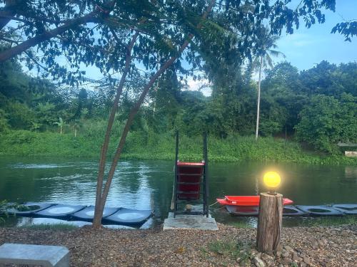 a dock with a chair and a boat in the water at ชลลดา ริเวอร์ โฮมสเตย์ แก่งกระจาน in Ban Wang Malako