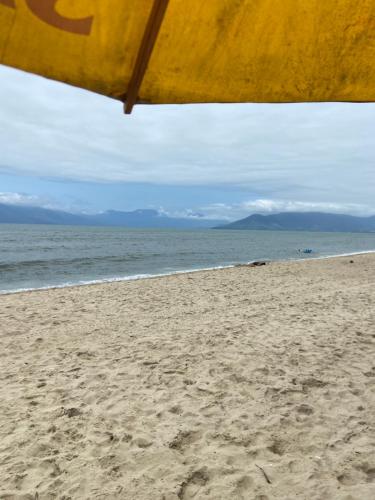 a view of the beach from under a beach umbrella at Desfrute bons momentos a beira mar com diária 24h in Caraguatatuba