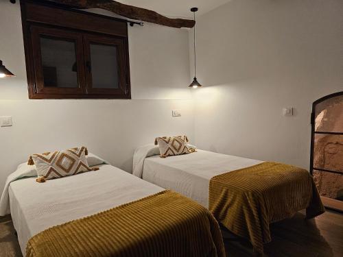 two beds in a room with white walls at El Mirador de Teo in Alocén