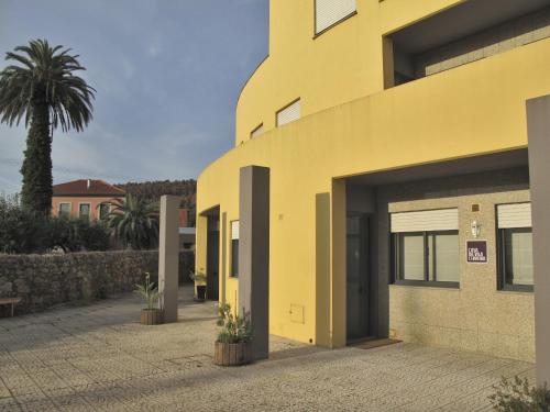 a yellow building with a palm tree in the background at Casa da Vila Cerveira in Vila Nova de Cerveira