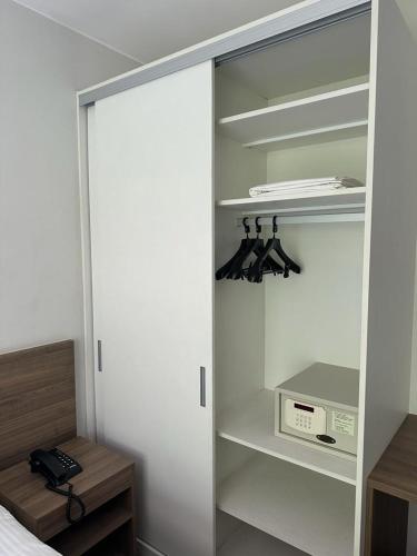 a bedroom with a closet with a bed and a microwave at Suíte com varanda em Via Premiere - Rio centro in Rio de Janeiro