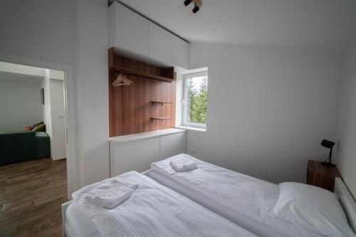 a white bedroom with a bed and a window at Kuca 59 in Jahorina