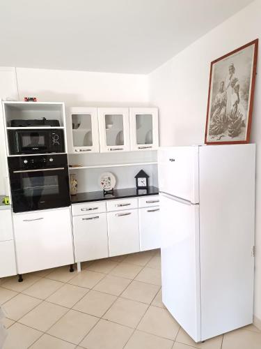 a white kitchen with white cabinets and appliances at La belle Martinique in Sainte-Luce