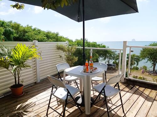 une table et des chaises sur une terrasse avec un parasol dans l'établissement La belle Martinique, à Sainte-Luce