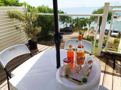 uma mesa com duas garrafas de álcool numa varanda em La belle Martinique em Sainte-Luce