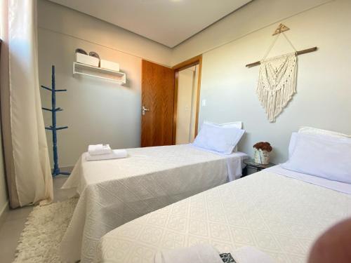 um quarto com duas camas com lençóis brancos em Oasis Urbano em Goiânia