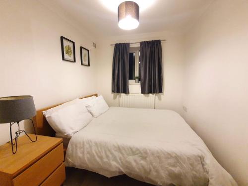 a bedroom with a bed and a lamp and a window at Accommodation in Stevenage 2 bedrooms in Stevenage