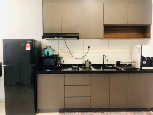 eine Küche mit einem schwarzen Kühlschrank und einer Mikrowelle in der Unterkunft The Maisonnette Homestay in Kajang