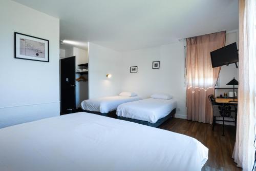 a hotel room with two beds and a desk at Kyriad Nuits-Saint-Georges in Nuits-Saint-Georges