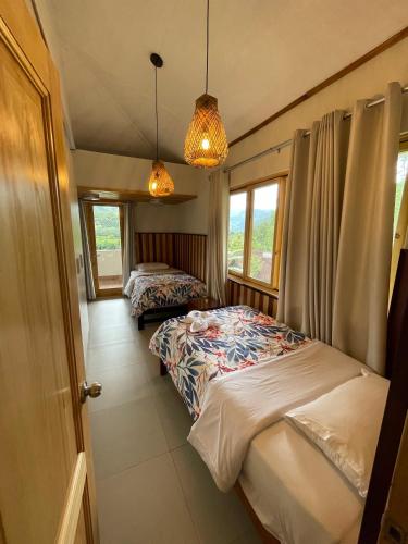 a bedroom with two beds and two windows at Mercedes Lodge in San Ramón