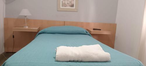 ein Bett mit einer blauen Decke und einem weißen Kissen in der Unterkunft Hotel Iberia in Neuquén