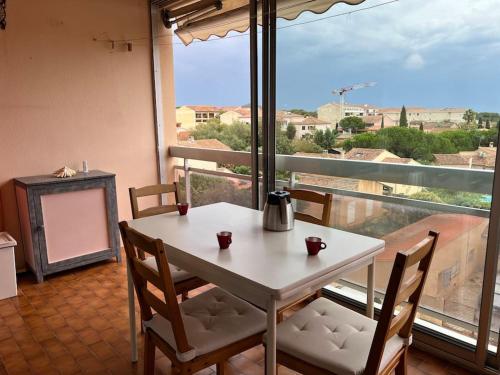une table et des chaises dans une pièce avec une grande fenêtre dans l'établissement Très bel appartement centre-ville pour 4 personnes, à La Londe-les-Maures