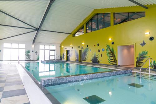 a swimming pool in a building with a yellow wall at Camping Pods Hedley Wood Holiday Park in Bridgerule