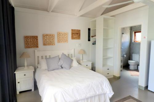 a white bedroom with a white bed and a bathroom at M & M Flat Arniston in Arniston