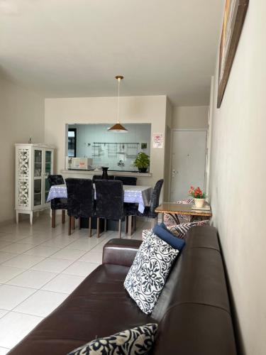 uma sala de estar com um sofá e uma sala de jantar em Apartamento amplo a menos de 400 metros da praia localizado próximo a praça da Brunella, área nobre do Guarujá. no Guarujá