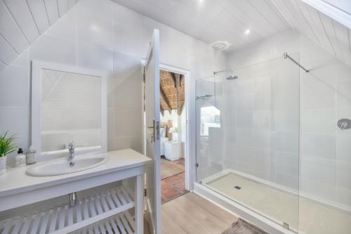 Un baño blanco con ducha y lavabo. en Longship In Arniston, en Arniston