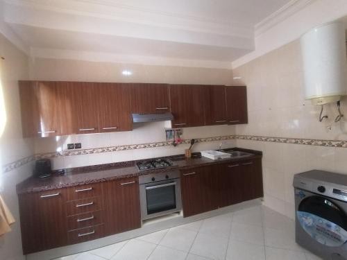 a kitchen with wooden cabinets and a stove top oven at Appartandalus in Larache