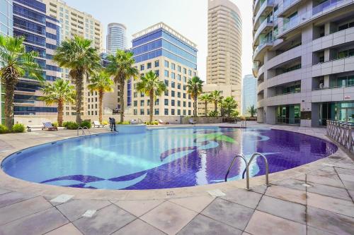 a large swimming pool in a city with tall buildings at LUXFolio Retreats - Spacious Luxury Unit - 3BHK in Dubai