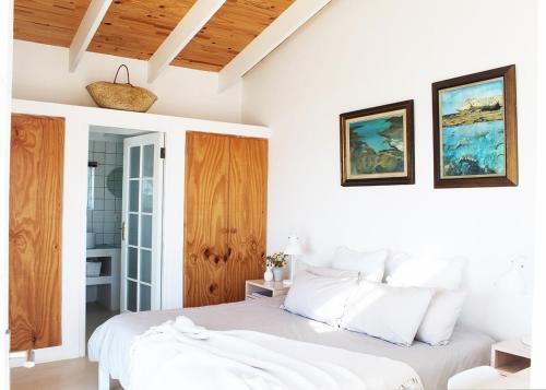 1 dormitorio con paredes blancas y 1 cama con almohadas blancas en The Palace - Sea View Arniston, en Arniston