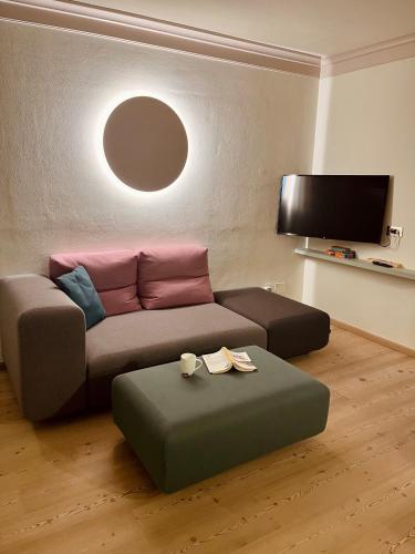 a living room with a couch and a ottoman at Rosa Alpina - Appartamento nelle Dolomiti in Dobbiaco