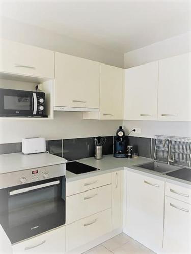 une cuisine avec des armoires blanches et un four à plaques de cuisson dans l'établissement Bel appartement proche du port, à Sanary-sur-Mer