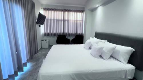 a bedroom with a white bed with white pillows at la casa del encanto in Tarapoto