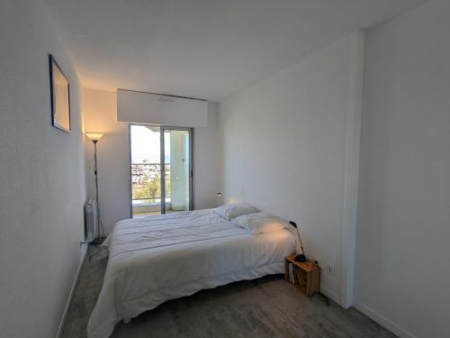 une chambre blanche avec un lit et une fenêtre dans l'établissement T2 cabine 35m2 au port d'Arcachon avec balcon et parking sécurisé - FR-1-420-28, à Arcachon