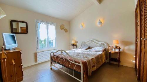 une chambre avec un lit, une télévision et une fenêtre dans l'établissement Jolie villa proche des plages et pistes cyclables, à La Couarde-sur-Mer