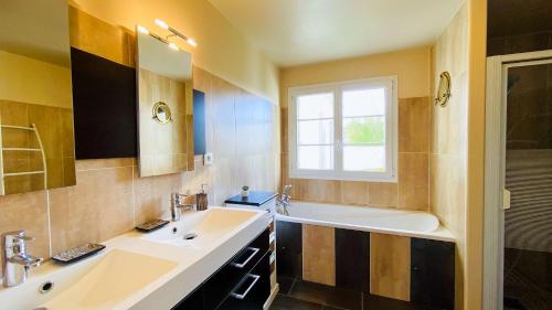 La salle de bains est pourvue de 2 lavabos, d'une baignoire et d'une fenêtre. dans l'établissement Jolie villa proche des plages et pistes cyclables, à La Couarde-sur-Mer