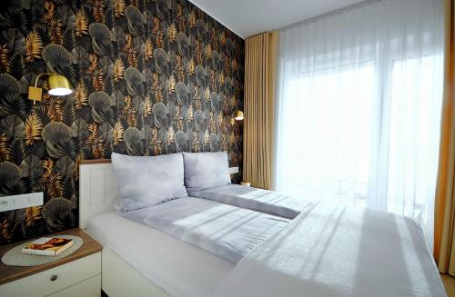 1 dormitorio con cama y pared con papel pintado de pájaro en Apartament Słoneczny Lux - Resort AQUA POLANKI - Baseny-Sauny-Siłownia-2023r en Kołobrzeg