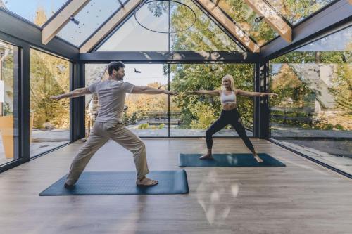 un hombre y una mujer haciendo yoga en una habitación con ventanas en Domek na drzewie Oddech, en Nałęczów