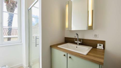 Un baño con lavabo y ventana. en Superbe appartement en plein centre village, en Saint-Martin-de-Ré