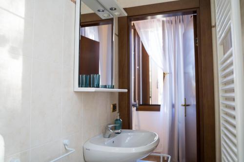 uma casa de banho com um lavatório, um espelho e uma janela em All’Altana b&b apartment em Marghera