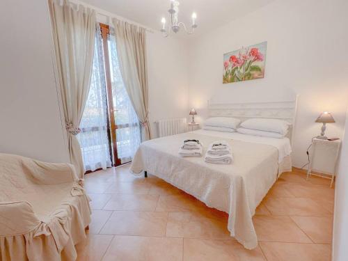 a white bedroom with a bed and a chair at Birgi holiday home in Marsala