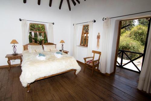 1 dormitorio con 1 cama, mesa y sillas en Las Casitas del Arco Iris, en Urubamba