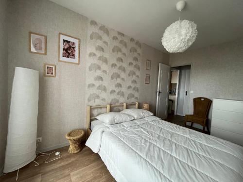 a bedroom with a large bed and a chandelier at L'Escale ensoleillée, 2 pièces sur le Port proche Juno Beach in Courseulles-sur-Mer