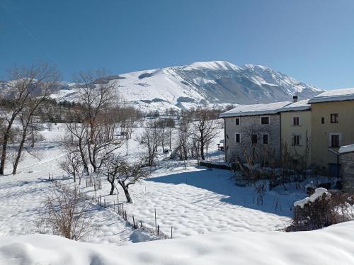 una casa nella neve con una montagna sullo sfondo di Famiglia nel vento a Caramanico Terme