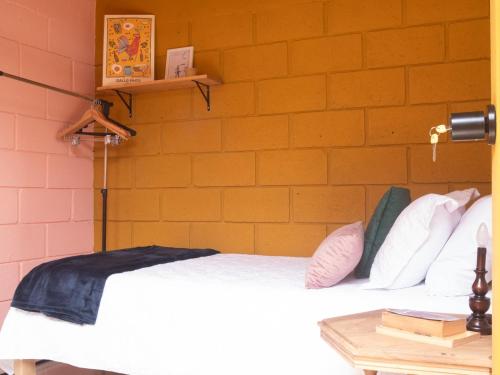 1 dormitorio con cama y pared de ladrillo en Lolas Hostal (Hab. privada) baño compartido, en San José