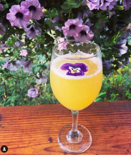 a glass of juice sitting on a wooden table with flowers at McKinley Creekside Cabins in McKinley Park