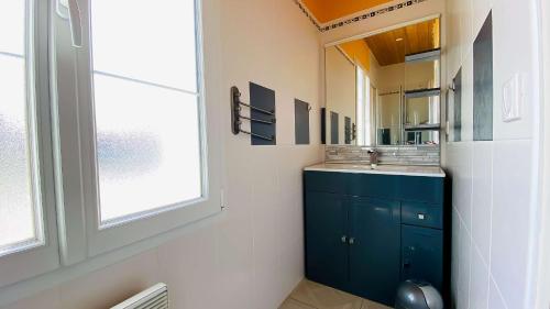 ein Badezimmer mit einem blauen Waschbecken und einem Spiegel in der Unterkunft Villa récente avec accès à la plage par chemin à l'arrière de la maison in Le Bois-Plage-en-Ré