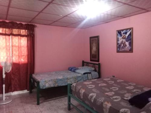 2 Betten in einem Zimmer mit rosa Wänden in der Unterkunft Beautiful villa for singles, couples, families and groups cozy stay in La Chorrera