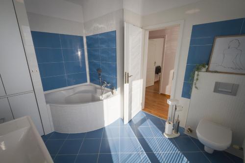 baño azul y blanco con bañera y aseo en Maisonette Apartment with Terrace en Koliba
