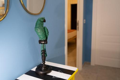 a green parrot sitting on a stand on a table at LA CASA DI ZOE in Manfredonia