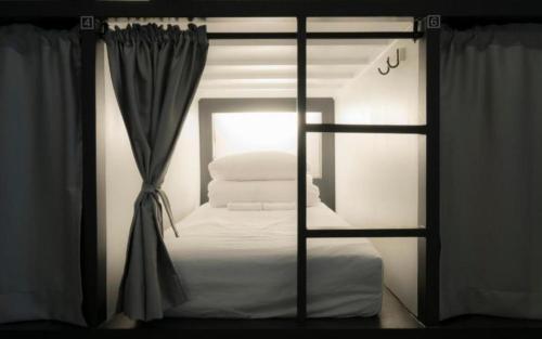 a room with a bed and a window with towels at CANVAS BLACK Guesthouse in Busan