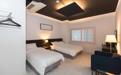 Habitación de hotel con 2 camas y sofá en CANVAS BLACK Guesthouse, en Busan