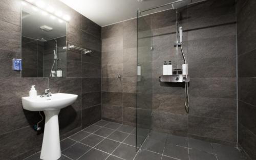 y baño con lavabo y ducha acristalada. en CANVAS BLACK Guesthouse, en Busan